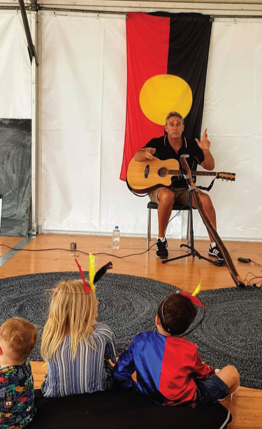 Amos playing guitar to school children at school